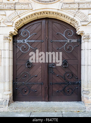 Große hölzerne Tür mit einem Griff, Schmiedeeisen Griff. Die Tür in den Tresor aus Sandstein. Stockfoto