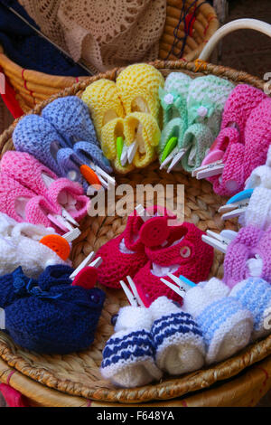 Weidenkorb voller Baby Bootie handgefertigt von einer alten Dame auf einer Seitenstraße in Sorrent Italien gemischte rosa blau Paare Peg gestrickt Stockfoto