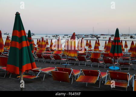 Strand-Schirme für die Nacht umgeklappt, Sonne setzen rote Glut in den Himmel Ende ein weiterer sehr heißer Tag in Positano dunkle Sand Bett Stockfoto