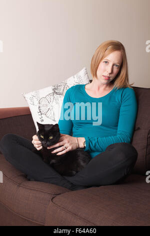 Eine Frau sitzt mit einem carwoman Holding eine Katze Stockfoto