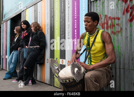 Drei unbekannte Mädchen hören Sie Straßenkünstler spielen seine Trommel in einer Straße am 7. April 2007 in Camden Town, London, UK. Stockfoto