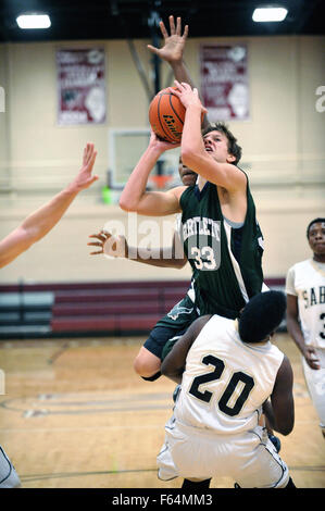 Player nimmt Kontakt aus dem Gegner, wie er weg beendet einen Angriff auf die Hoop während einer High School Basketball Spiel. USA. Stockfoto