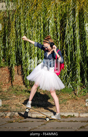 Ballerina-Hipster bei einem Spaziergang durch den herbstlichen Park. Mädchen Musik über Kopfhörer hören. Ein Mädchen trägt ein Tutu und sneakers Stockfoto