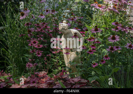 Stauden, die rund um eine Steinstatue. Stockfoto