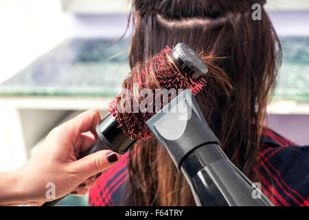 Bürsten der langen braunen Haares einer Frau in ihrem Friseursalon Friseur Stockfoto