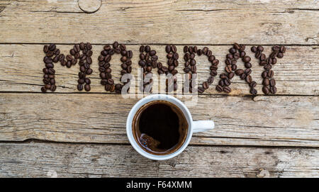 Tasse Kaffee auf hölzernen Hintergrund und Montag Kaffeebohnen Stockfoto