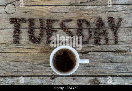 Tasse Kaffee auf hölzernen Hintergrund und Dienstag Kaffeebohnen Stockfoto
