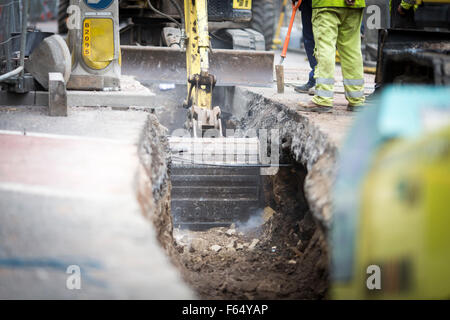 ein Bagger einen Graben in einer Straße Stockfoto
