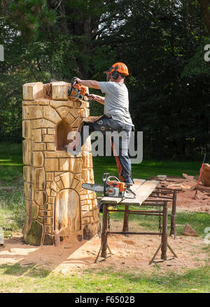 Eine Kettensäge Bildhauer schaffen eine Turm-Skulptur aus einem Baumstamm auf den Cranborne Chase Woodfair, Wiltshire, UK Stockfoto