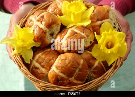 Eine Frau stellt Hot Cross Buns dekoriert mit Narzissen in einem rustikalen Weidenkorb für die Osterfeiertage in Nord-England, UK Stockfoto