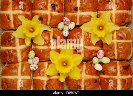 Hot Cross Buns dekoriert mit Narzissen und Schokoladeneier zu Ostern Hintergrund blau kariert "Gingham", England UK Stockfoto