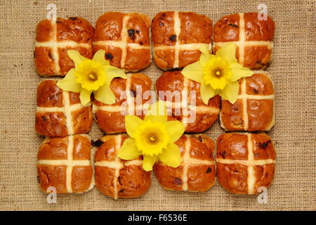 Hot Cross Buns dekoriert mit Narzissen und Schokoladeneier zu Ostern vor dem Hessischen Hintergrund, England UK Stockfoto