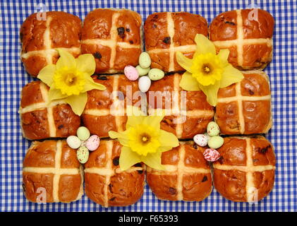 Hot Cross Buns dekoriert mit Narzissen und Schokoladeneier zu Ostern Hintergrund blau kariert "Gingham", England UK Stockfoto