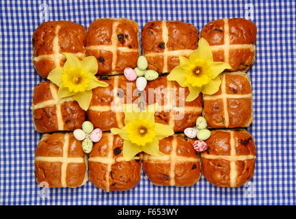 Hot Cross Buns dekoriert mit Narzissen und Schokoladeneier zu Ostern Hintergrund blau kariert "Gingham", England UK Stockfoto