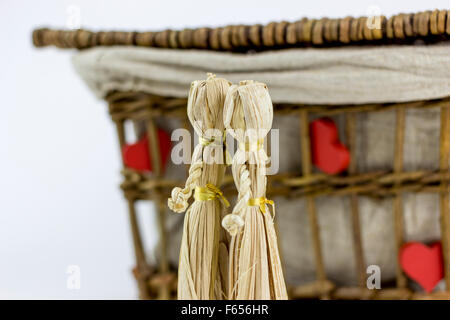 Zwei Stroh Puppen küssen vor einer alten Rattan Box auf weißem Hintergrund Stockfoto