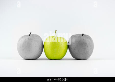 Drei grüne Äpfel auf einem weißen Hintergrund, mittlere einer entsättigt Stockfoto