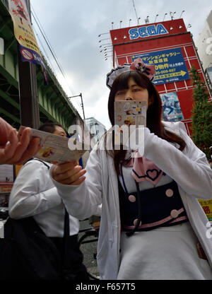 Tokio, Japan. 11. November 2015. Popularität der Maid Cafés in Akihabara Bezirk von Tokio, Japan, führte zu mehr Wettbewerb und ungewöhnlichen Taktiken, um Kunden zu gewinnen. Sehen Sie hier eine junge Frau in ein französisches Dienstmädchen Kostüm Flyer, damit geht die um Passanten zu erbitten. © Rory frohe/ZUMA Draht/Alamy Live-Nachrichten Stockfoto