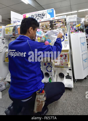 Tokio, Japan. 11. November 2015. Ein Arbeiter in Spielzeug-Abgabe Maschinen namens "Gacha Gacha", benannt nach dem Griff-drehen-Lärm, der die Freisetzung von Kunststoffkapsel, in Akihabara vorausgeht Gießen '' Spielzeug Kapseln '' station, Tokio, Japan. © Rory frohe/ZUMA Draht/Alamy Live-Nachrichten Stockfoto