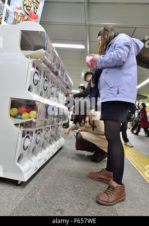 Tokio, Japan. 11. November 2015. Abend Pendler im Bahnhof Akihabara, Tokyo, Japan namens mit Spielzeug-Abgabe Maschinen "Gacha Gacha", benannt nach dem Griff-drehen-Lärm, der die Freisetzung von dem Kunststoffkapsel vorausgeht. © Rory frohe/ZUMA Draht/Alamy Live-Nachrichten Stockfoto