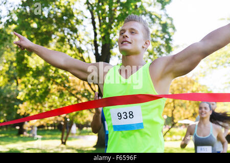 glückliche junge männliche Läufer gewinnen auf Rennen beenden Stockfoto