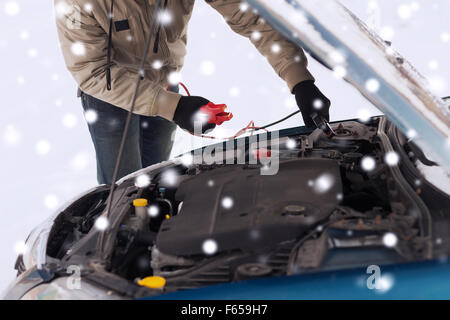 Nahaufnahme des Menschen unter Motorhaube mit Starter-Kabel Stockfoto