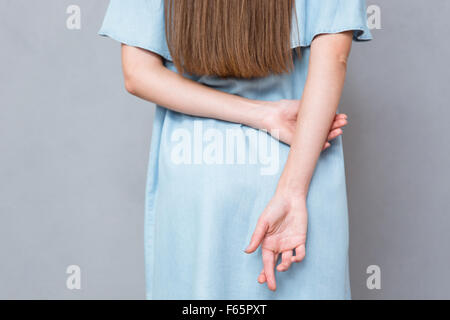 Nahaufnahme von gekreuzten Fingern hinter Rücken Frau Stockfoto