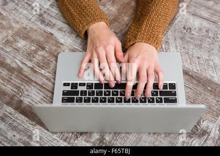 Draufsicht Nahaufnahme der weiblichen Hände in braunen Pullover auf Laptoptastatur tippen Stockfoto