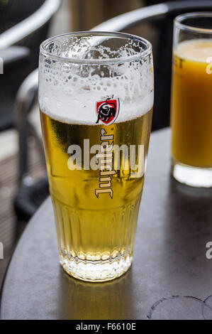 Ein bedrucktes Glas Jupiler Pils Bier an einer Bar Tisch, Bergues, Nord-Pas-de-Calais, Ile de France, Frankreich pub Tabelle getränke Gläser Stockfoto