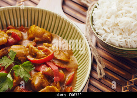 Curry gehackte Schweinefleisch in einer Schüssel mit Basmati-Reis auf einem Bambus Tischset auf einem blauen Holztisch Stockfoto