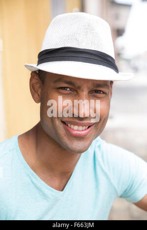 Schuss in den Kopf eines jeden ethnischen Menschen Lächeln auf den Lippen tragen ein Licht blau grün T-shirt und Schwarzweiß fedora Stockfoto