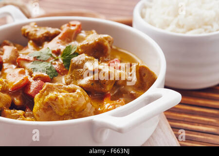 Curry gehackte Schweinefleisch in einer Schüssel mit Basmati-Reis auf einem Bambus Tischset auf einem blauen Holztisch Stockfoto