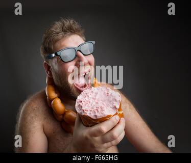 Hungriger dicker Mann mit Wurst um den Hals isst eine große Wurst in grau Stockfoto