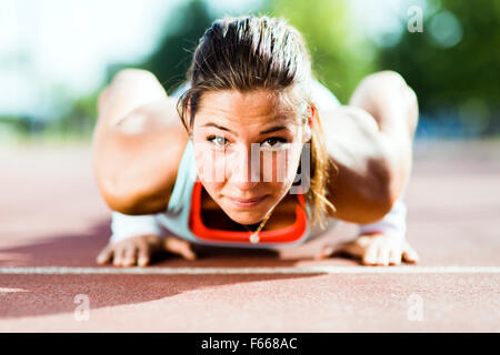 Junge schöne Frau doing Push-ups im Freien an einem heißen Sommertag konzentriert Stockfoto