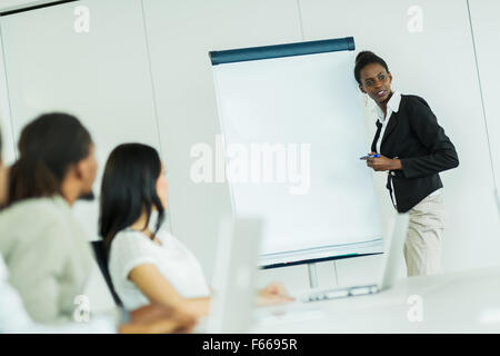 Junge Geschäftsleute, die an einem Konferenztisch sitzend und an ihre Kollegen zuhören und lernen neue Technologien Stockfoto