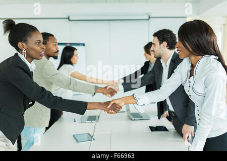 Geschäftsleute, die Hände zu schütteln, bevor Sie sich an einem Konferenztisch Stockfoto
