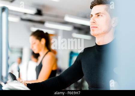 Gruppe von gesunden jungen Menschen mit Laufband und Crosstrainer im Fitness-Studio Stockfoto