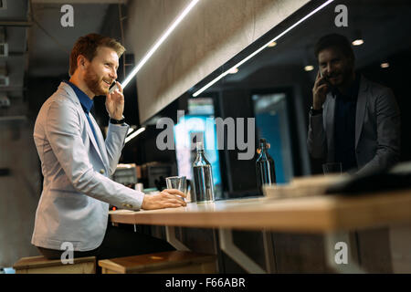 Anstrengenden Geschäftsmann telefonieren beim Sitzen in einer Kneipe Stockfoto