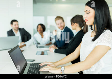 Geschäftsfrau, die auf einem Laptop in einem Büro arbeiten, während brainstorming Stockfoto