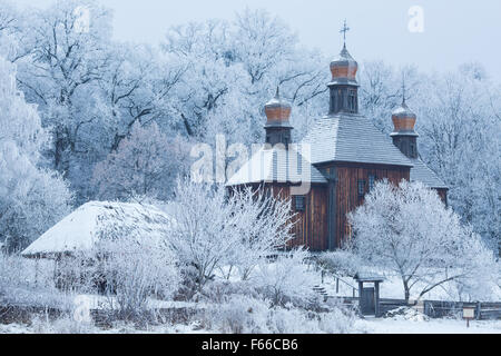 eine alte Kirche aus Holz unter den Bäumen im Schnee Stockfoto