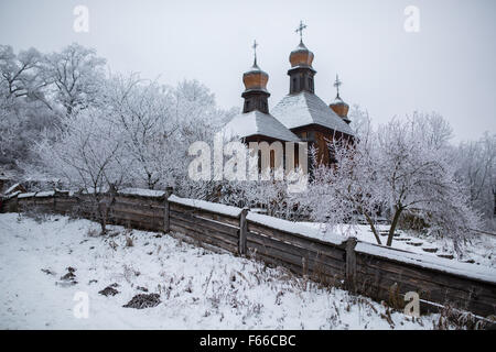 eine alte Kirche aus Holz unter den Bäumen im Schnee Stockfoto