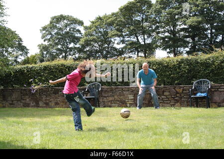 Vater und Sohn zusammen im Garten Fußball zu spielen Stockfoto