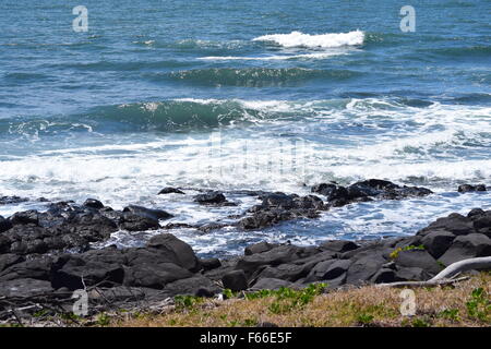 Felsige Landschaftsfoto mit Wellen aus dem Ozean in Australiens Sonnenstaat Queenland Rollen. Stockfoto