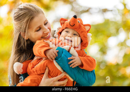 Junge Frau und ihr Baby Sohn im Herbst Park, junge in Fuchs Kostüm gekleidet Stockfoto