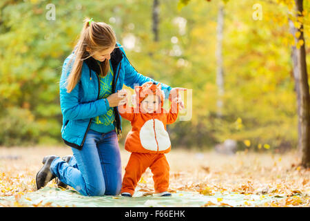 Junge Frau und ihr Baby Sohn im Herbst Park, junge in Fuchs Kostüm gekleidet Stockfoto