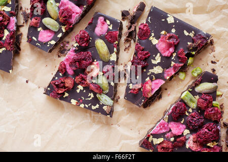 Handgeschöpfte Schokolade mit Beeren, Jpistachios und Essbares gold Stockfoto