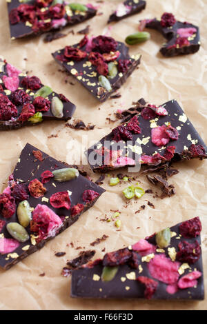 Handgeschöpfte Schokolade mit Beeren, Jpistachios und Essbares gold Stockfoto