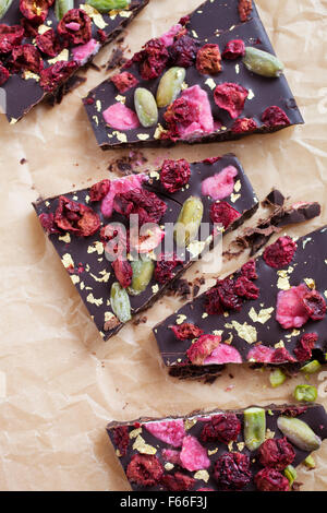 Handgeschöpfte Schokolade mit Beeren, Jpistachios und Essbares gold Stockfoto