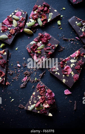 Handgeschöpfte Schokolade mit Beeren, Jpistachios und Essbares gold Stockfoto