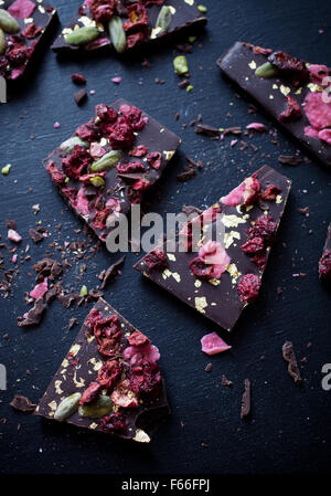 Handgeschöpfte Schokolade mit Beeren, Jpistachios und Essbares gold Stockfoto