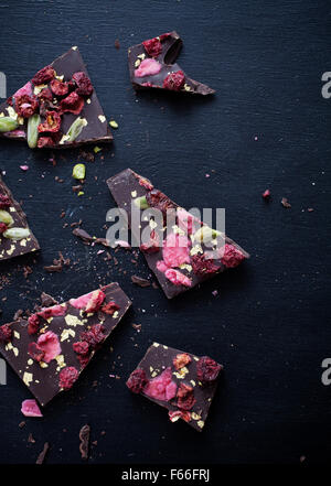 Handgeschöpfte Schokolade mit Beeren, Jpistachios und Essbares gold Stockfoto